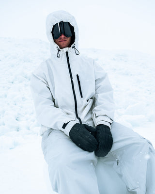 Person wearing a white snowsuit sitting in the snow