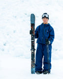 BUSI Biggie Pant Navy snowboard and ski pants, on model in the snow with skis
