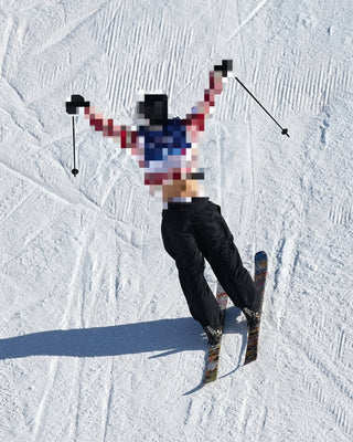 Person skiing on a snowy slope with arms raised