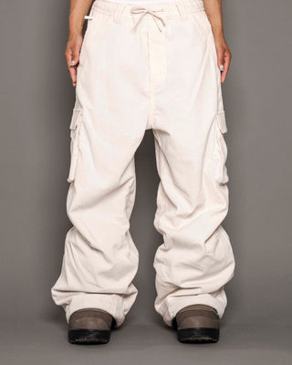 White cargo pants worn by a person on a gray background
