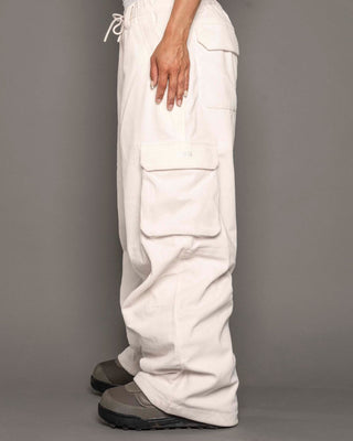 White cargo pants worn by a person on a gray background
