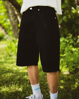 Person wearing black shorts and white socks with blue text, standing in a grassy area.