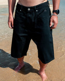 BUSI Biggie Shorts Black denim shorts, front view on model on the beach